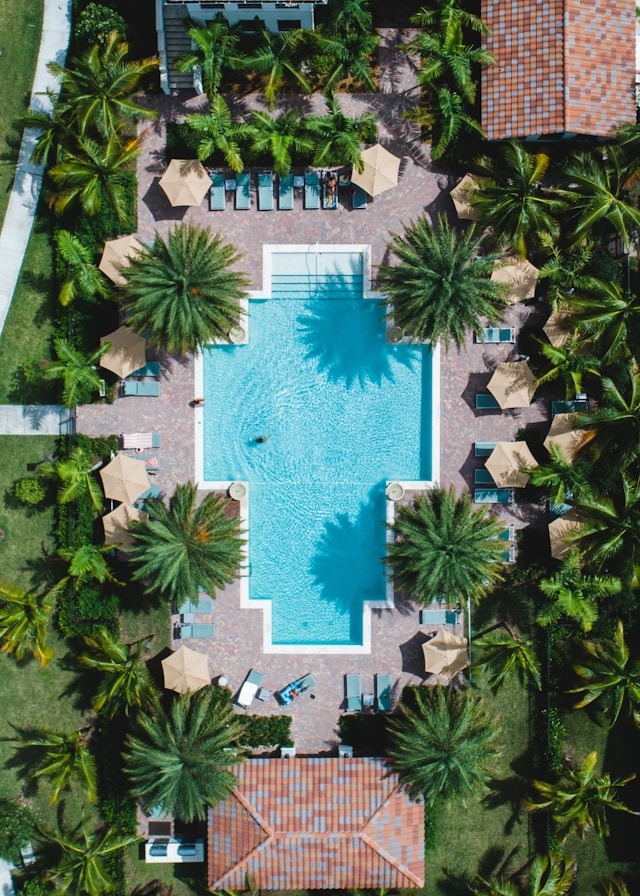 Arial shot of a Florida community center/clubhouse showing the pool area surrounded by palm trees