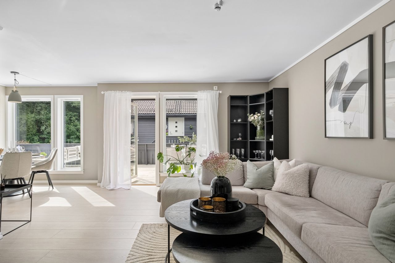 bright modern living room, with a large sliding patio door, beige sectional and round black coffee table on a sisal rug
