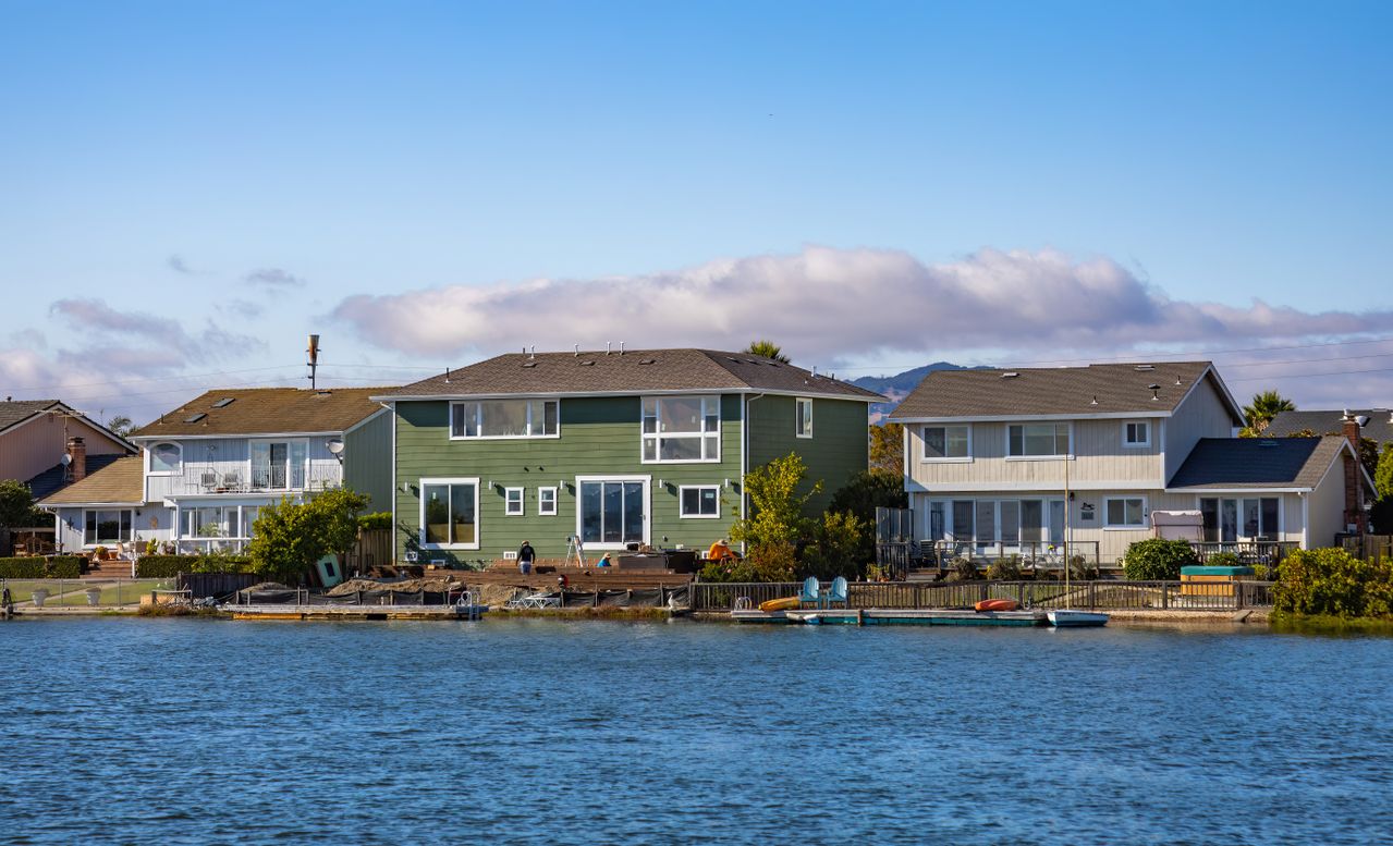 Picturesque lakeside homes with clear blue skies and calm water in a peaceful neighborhood.