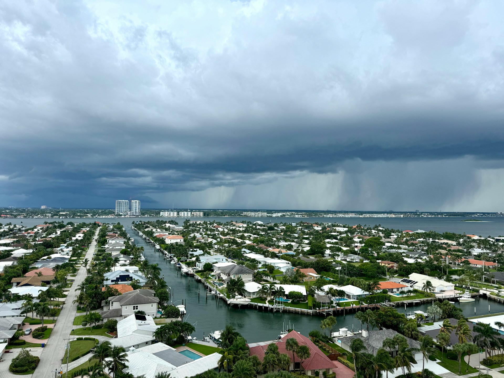 an arial shot of a storm blowing into a Florida neighborhood, showing homes and yards below a menacing cloud